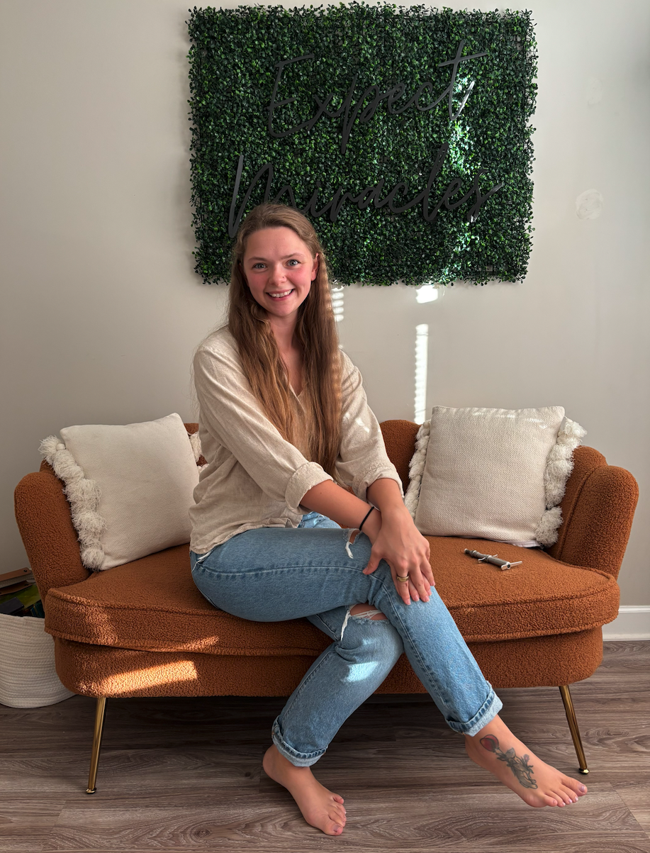 Dr. Shannon Bramlett, D.C., smiling on the couch in her Travelers Rest office
