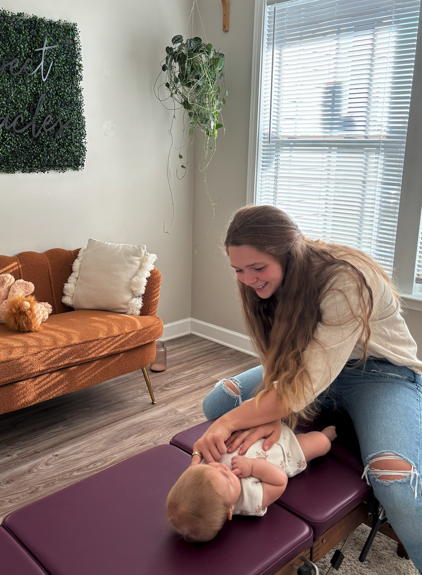 Dr. Shannon smiling while gently adjusting a baby on the office table
